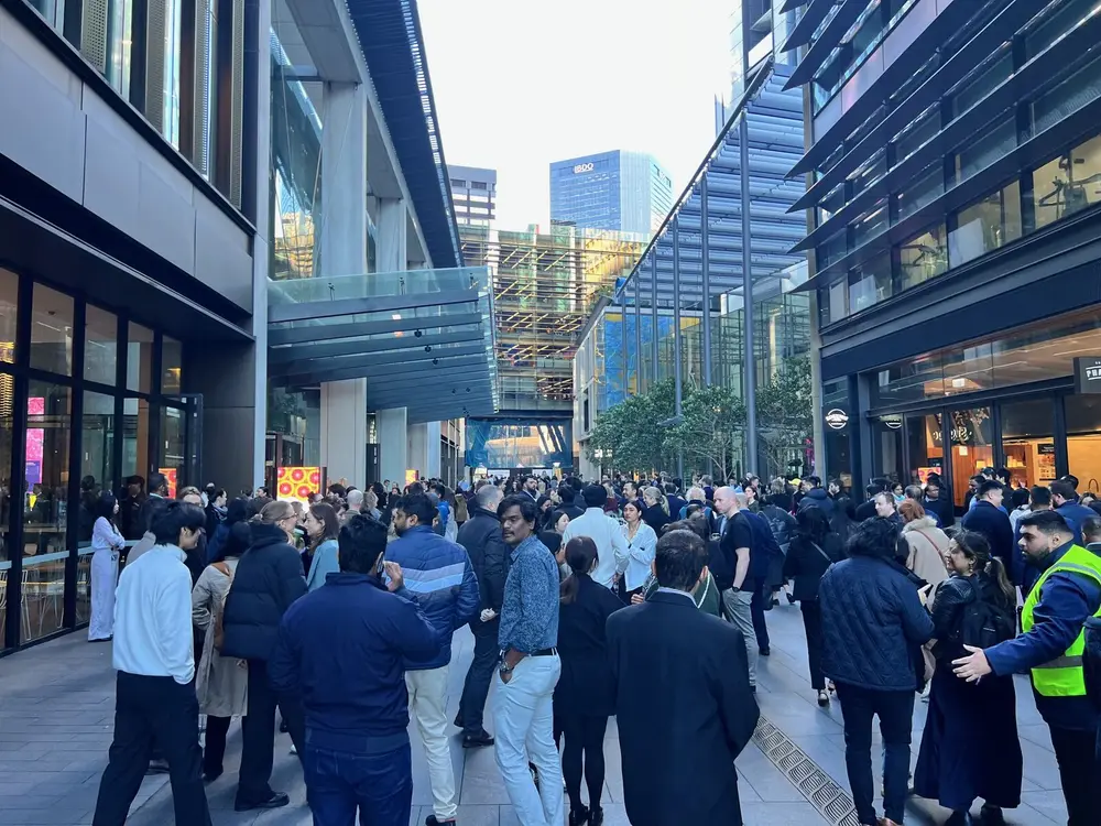 Office workers assembling in a city laneway after evacuating, wardens in hi-vis among them.