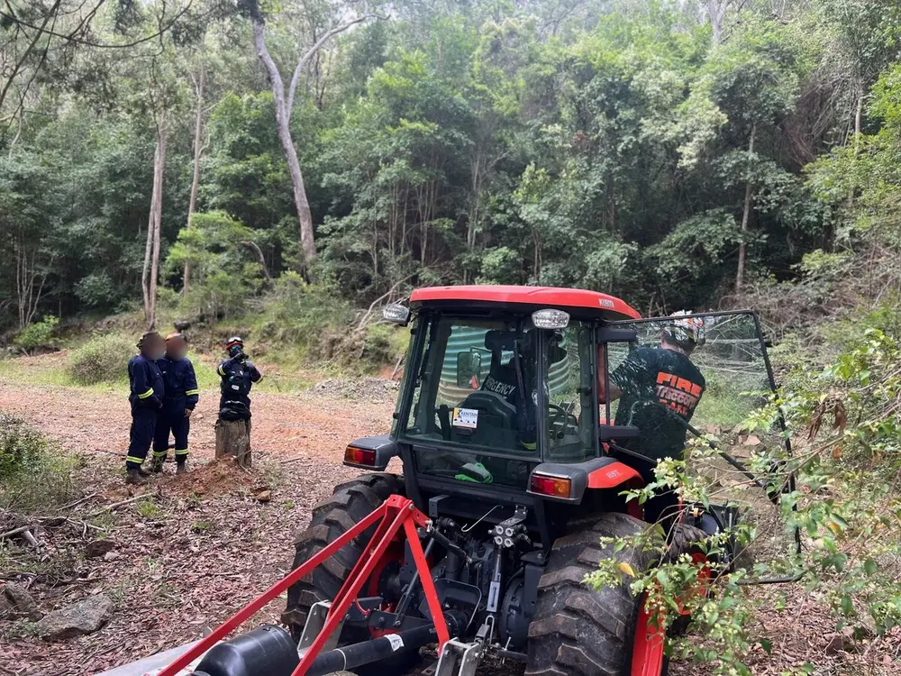 Tractor and slasher opening up a fire trail, with the crew standing by.